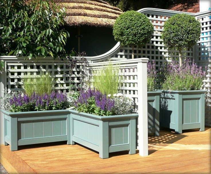 three planters with plants in them on a wooden deck