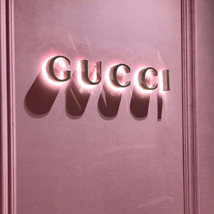 the word gucci is lit up against a pink wall