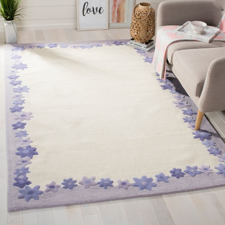 a white rug with purple flowers on the floor in a living room next to a couch