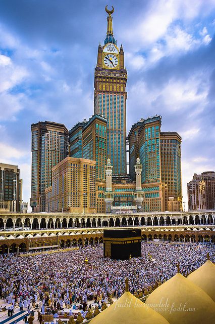 a large group of people standing in front of a tall building with a clock on it