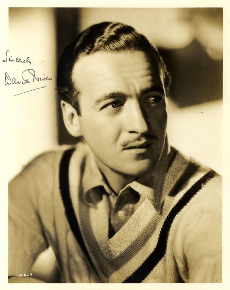 an old black and white photo of a man wearing a sweater over a striped shirt