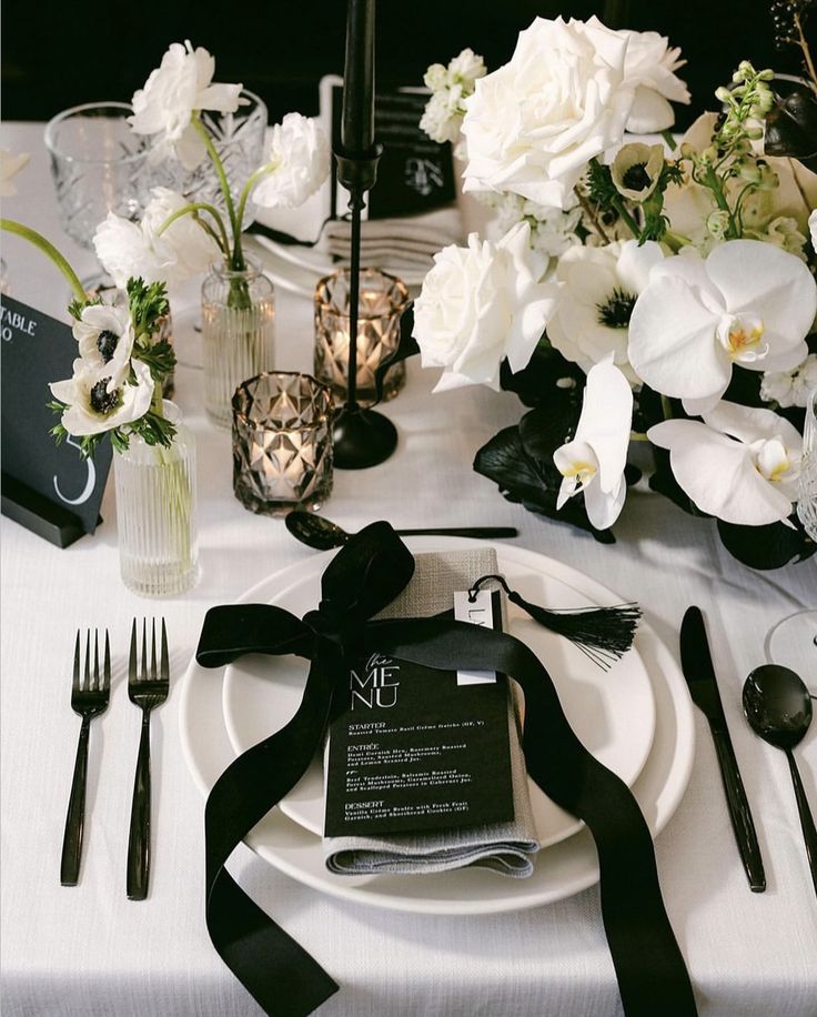 the table is set with white flowers and black napkins for an elegant wedding reception