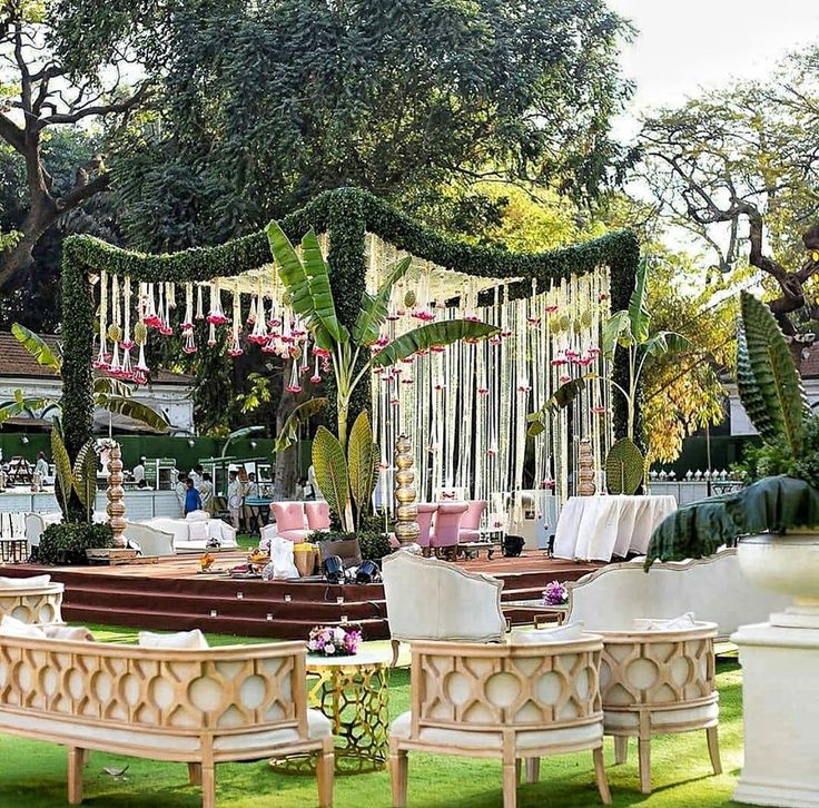 an outdoor wedding setup with white chairs and greenery