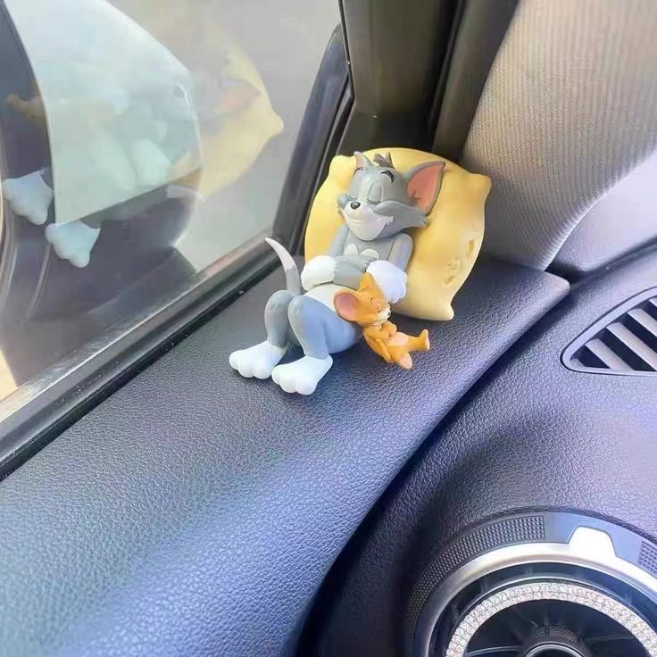 a toy mouse sitting on the dashboard of a car with its head in the center console