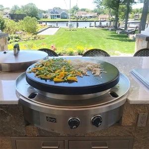 an outdoor grill with various vegetables cooking on it's burners and in front of a large grassy area