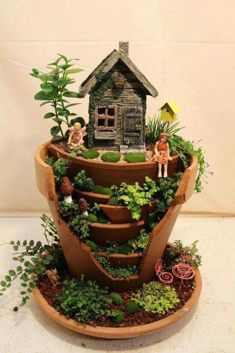 a potted planter filled with plants and miniature people in front of a house