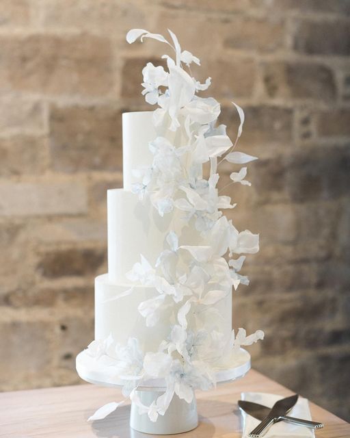 a white wedding cake with flowers on it and a pair of scissors next to it