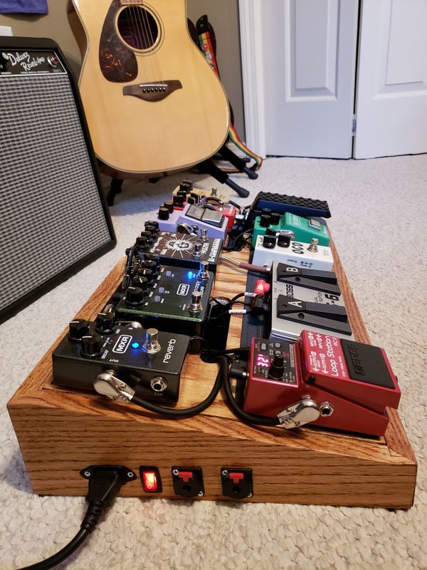 an array of electronic devices sitting on top of a wooden table next to a guitar