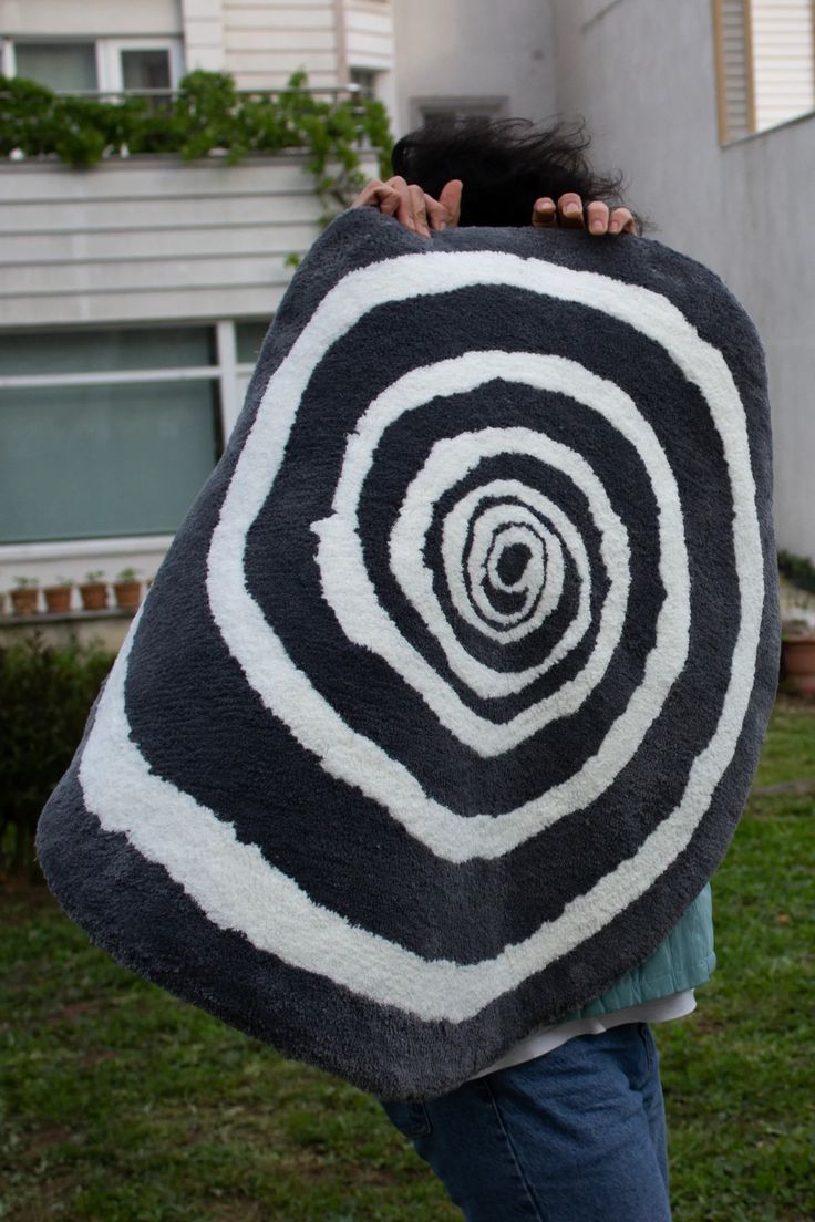 a woman is wrapped in a black and white blanket with a spiral design on it