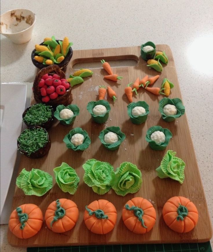 a cutting board topped with cupcakes covered in green frosting and decorated as pumpkins