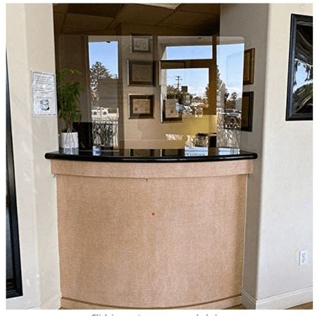 the front desk of a hotel lobby with a potted plant on it's counter