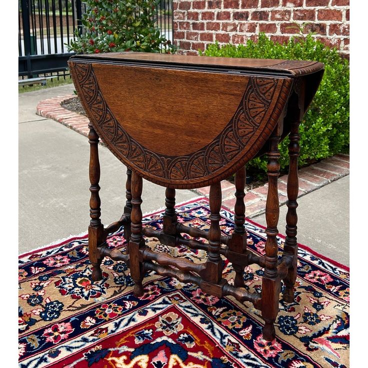 an old wooden table sitting on top of a rug next to a brick wall and fence