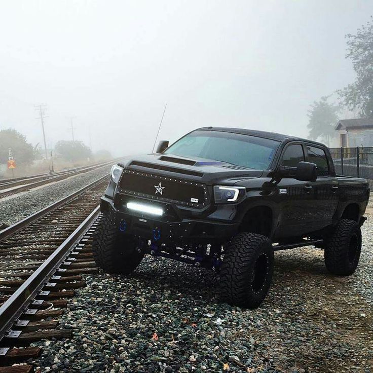 a black truck parked on train tracks in the fog