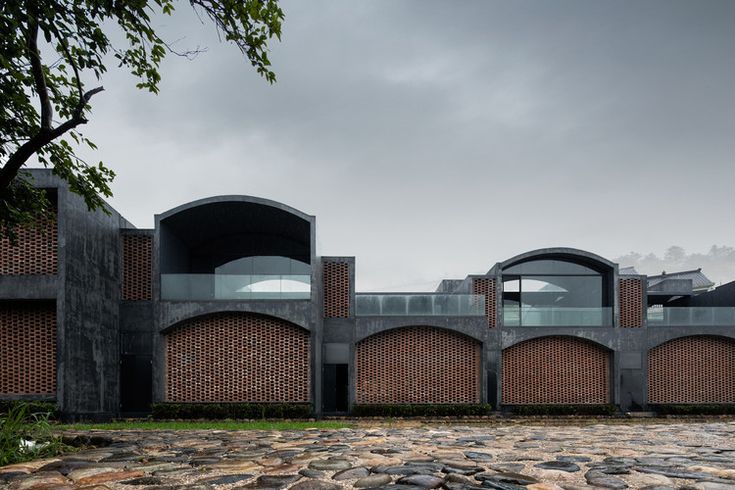 a brick building with arched windows on the top floor and stone walkways leading up to it