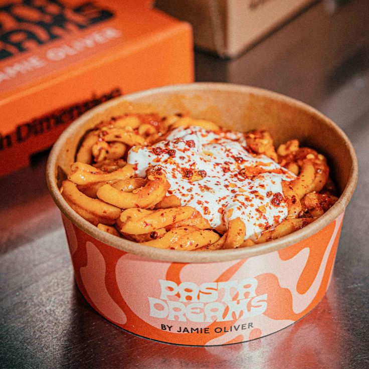 a bowl of food sitting on top of a table next to a box of orange juice