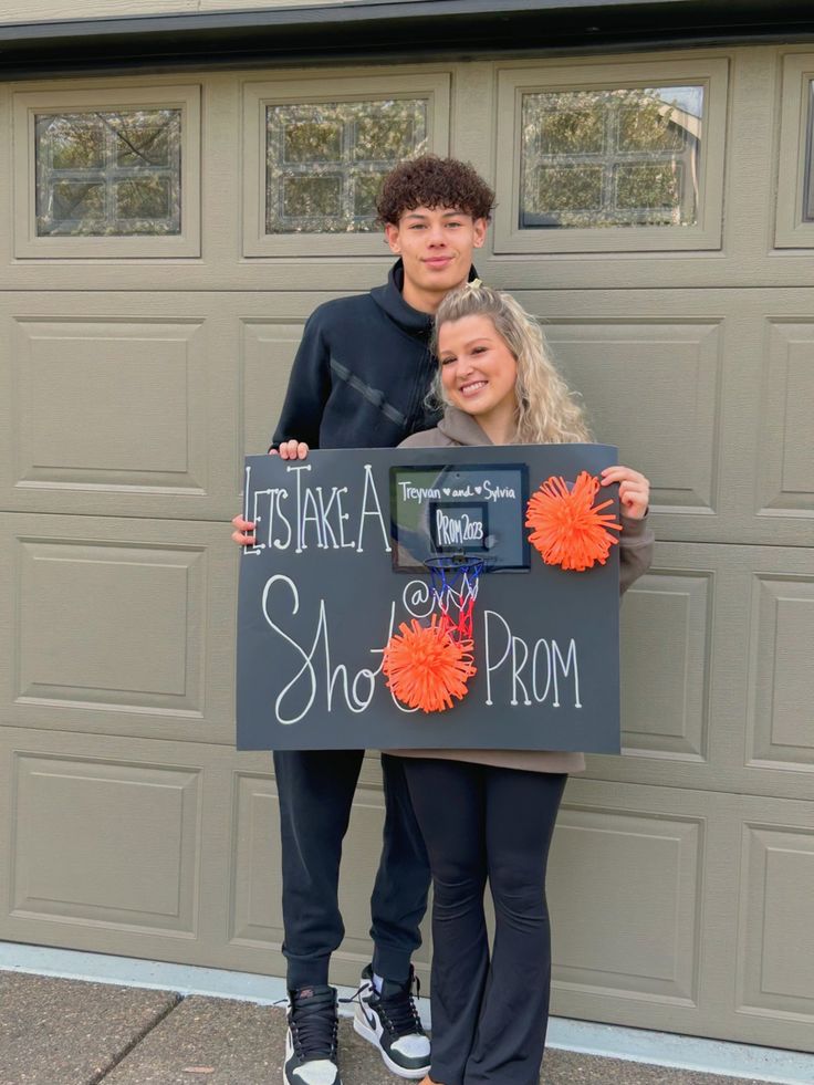 two people standing in front of a garage holding a sign that says it's like a shoe prom