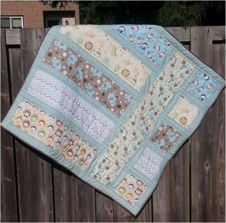 a baby quilt hanging on a wooden fence