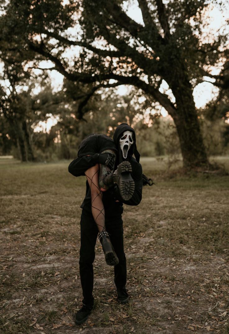 a person in a skeleton mask holding a baseball mitt and wearing a black outfit