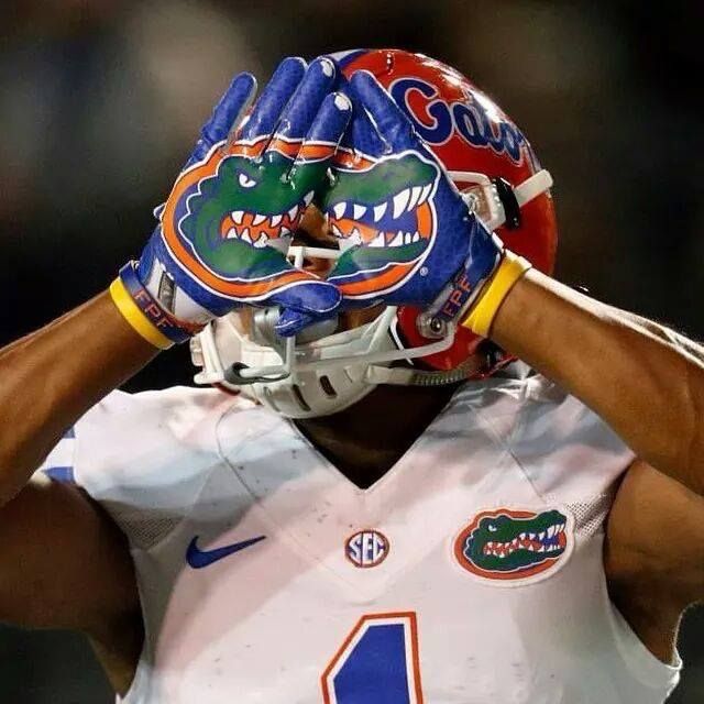 a football player wearing a florida gators helmet and holding his hands to his face