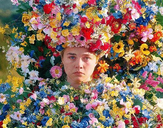 a woman with flowers on her head in front of a television screen that is displaying the image