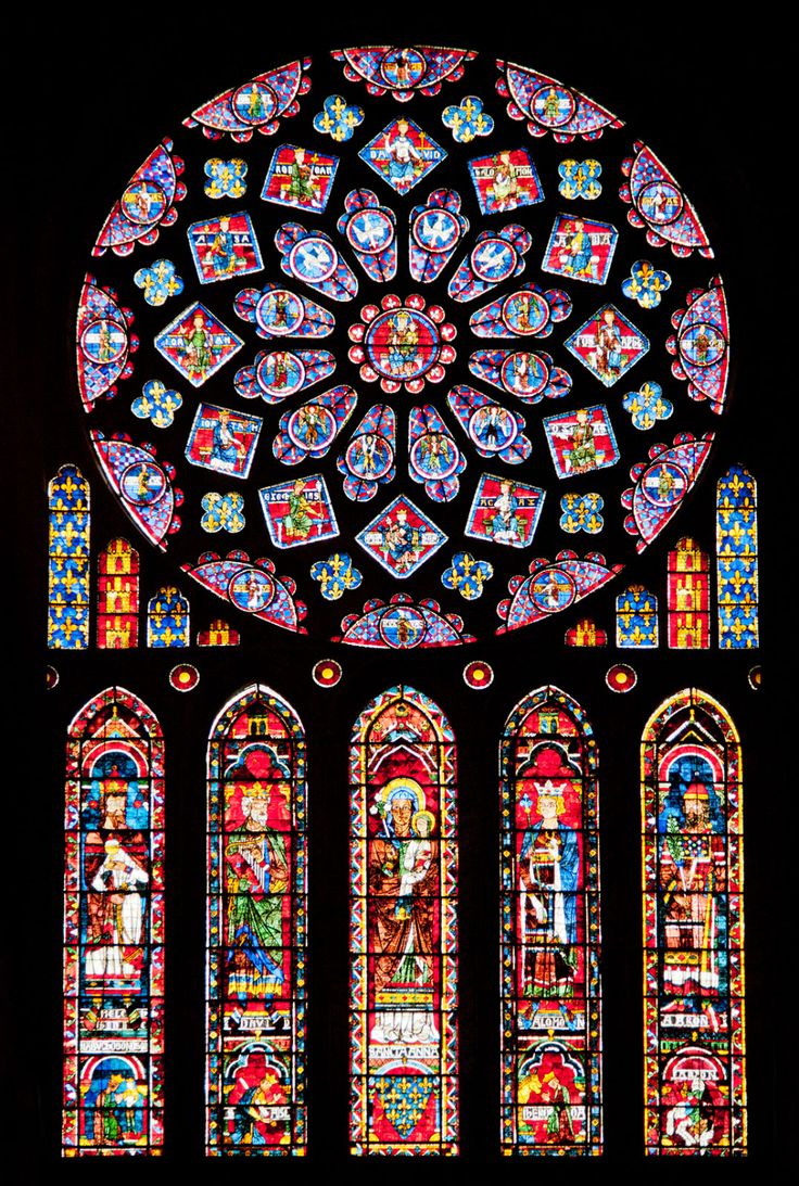 a large stained glass window in the middle of a dark room with many different colored windows