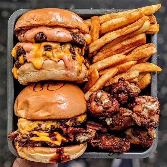 a tray filled with three cheeseburgers and french fries next to some onion rings