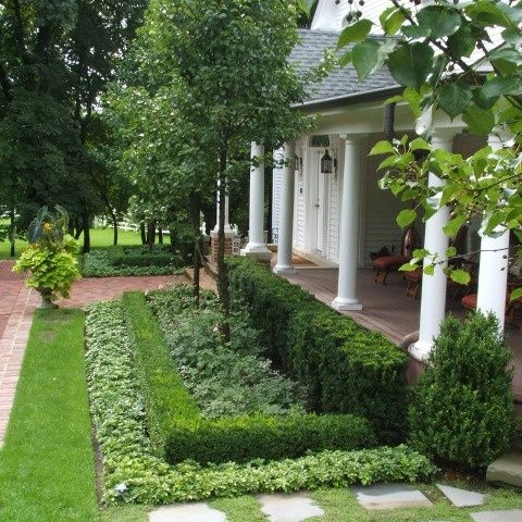 a house with a garden in front of it and some trees on the other side