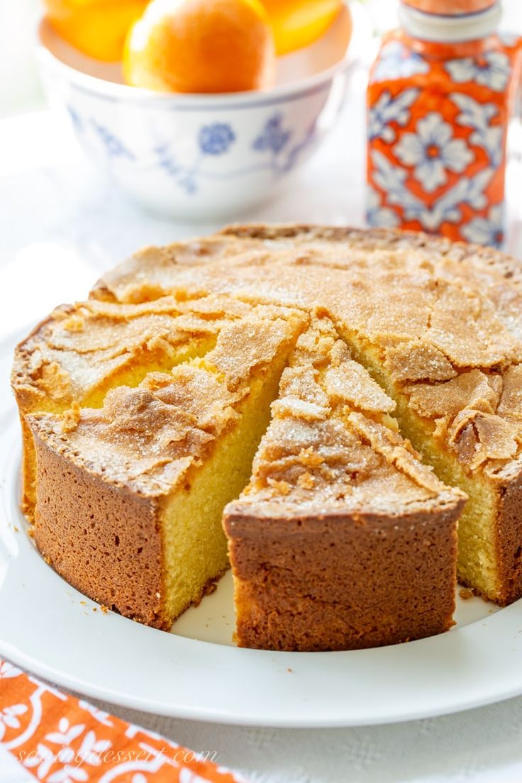 a cake on a plate with oranges in the background