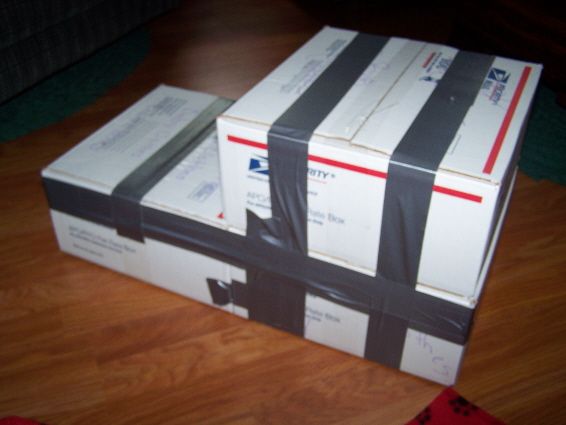 three boxes stacked on top of each other with black and white ribbons around them, sitting on a wooden floor