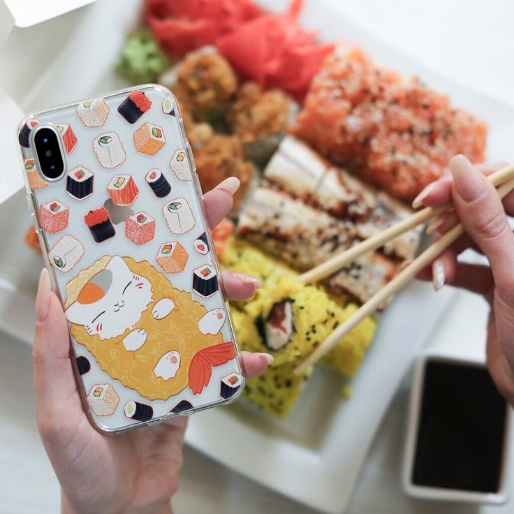 a woman holding up her phone case with sushi on it and chopsticks