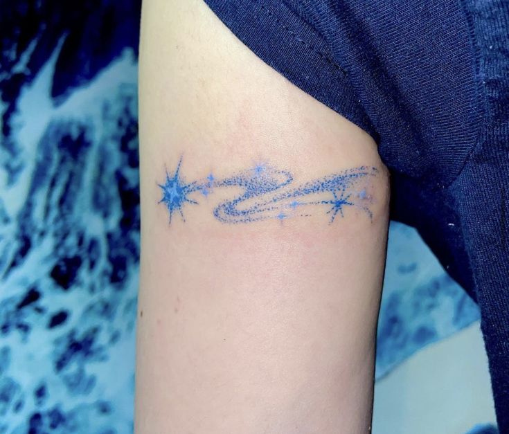 a woman's arm with a tattoo on it that has blue stars in the middle