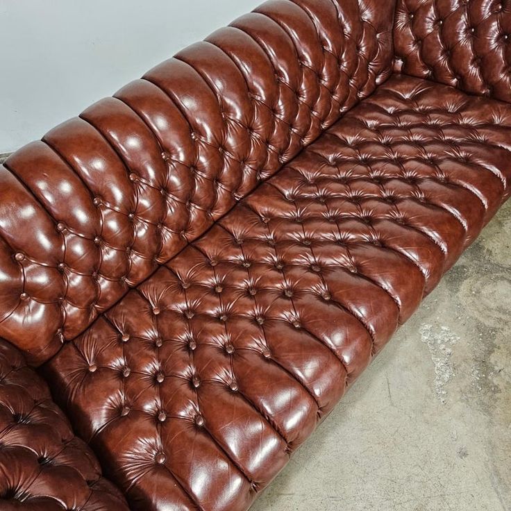 a brown leather couch sitting on top of a cement floor