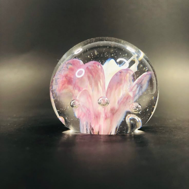 a glass ball with pink and white designs on it sitting on top of a table