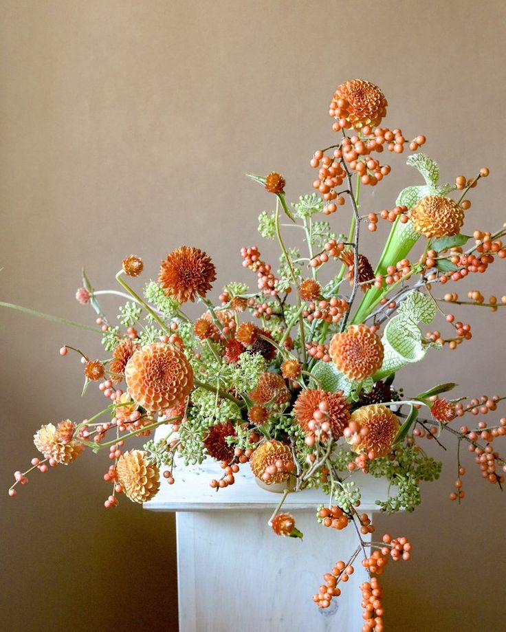 a white vase filled with lots of orange flowers