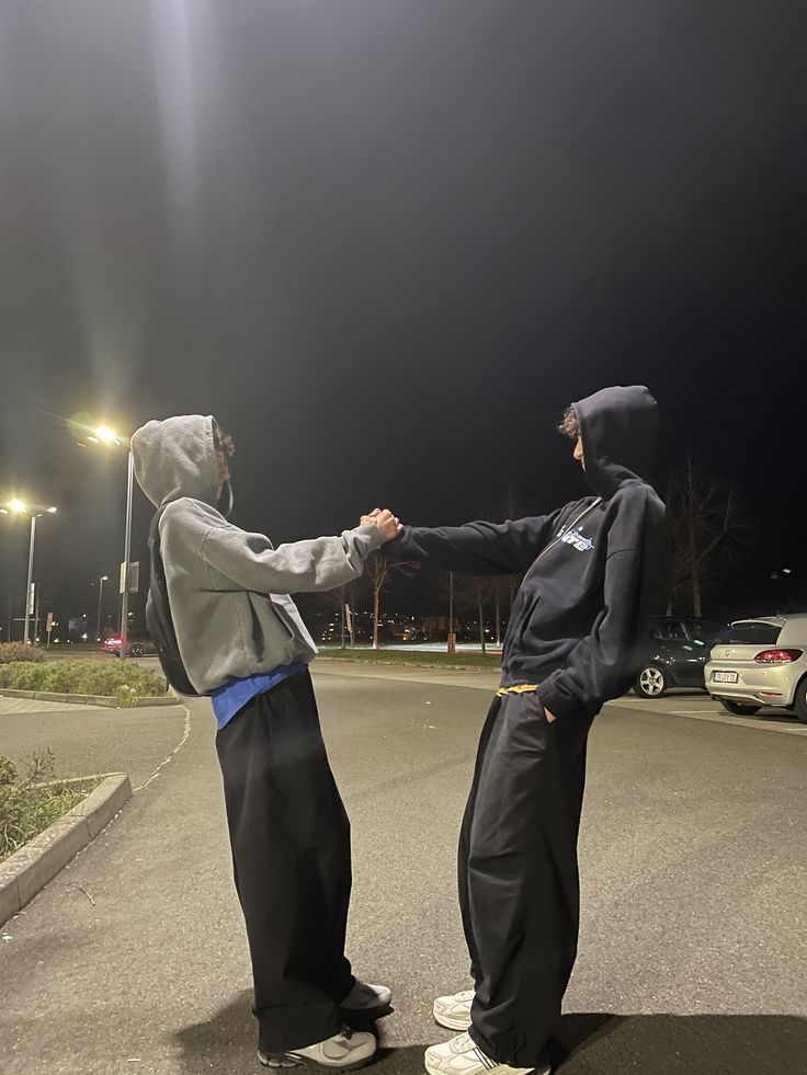 two young men standing in the middle of a parking lot holding each other's hands