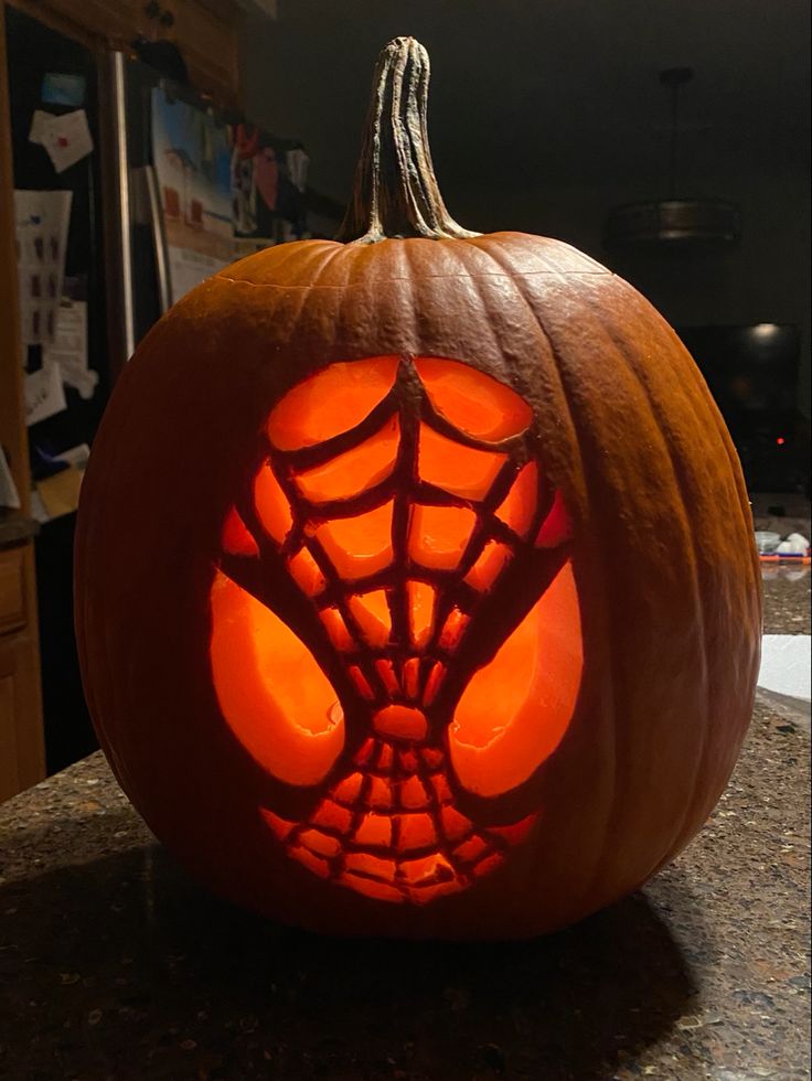 a pumpkin carved to look like a spiderman's web - net on it