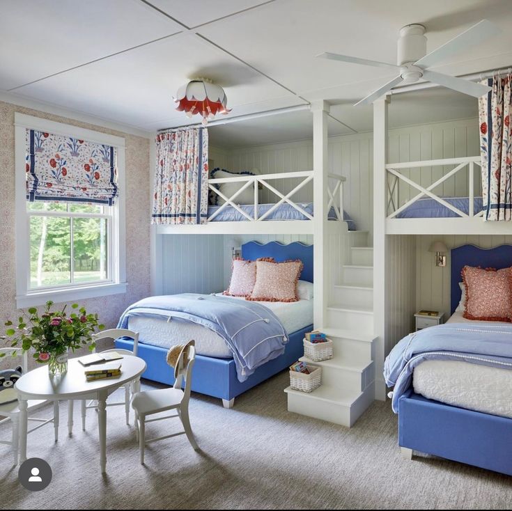 a bedroom with bunk beds and blue bedding in the corner, along with a table and chairs