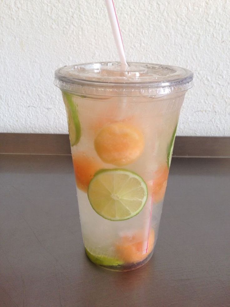 a drink with lime and oranges in it on a table next to a wall