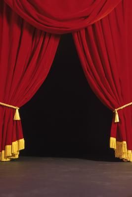 a red curtain with gold tassels is opened to reveal a stage scene or show