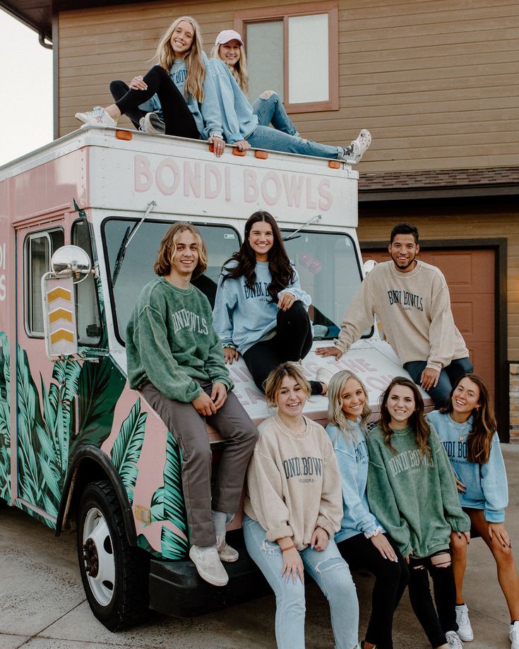 a group of people sitting on the back of a food truck in front of a house