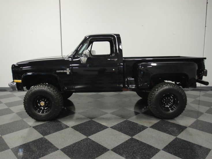 a black pickup truck parked on top of a checkered floor