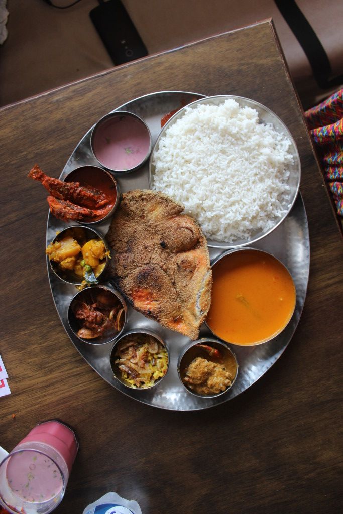 a metal plate topped with lots of different types of food on top of a wooden table