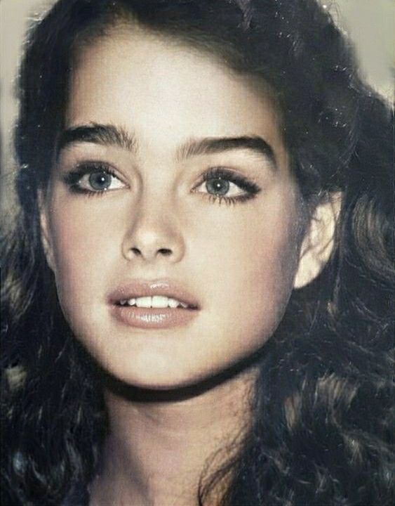 an old photo of a young woman with long hair and blue eyes, wearing a tiara