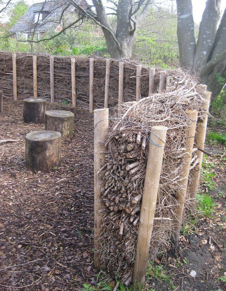 a pile of wood sitting in the middle of a field next to a fence and trees