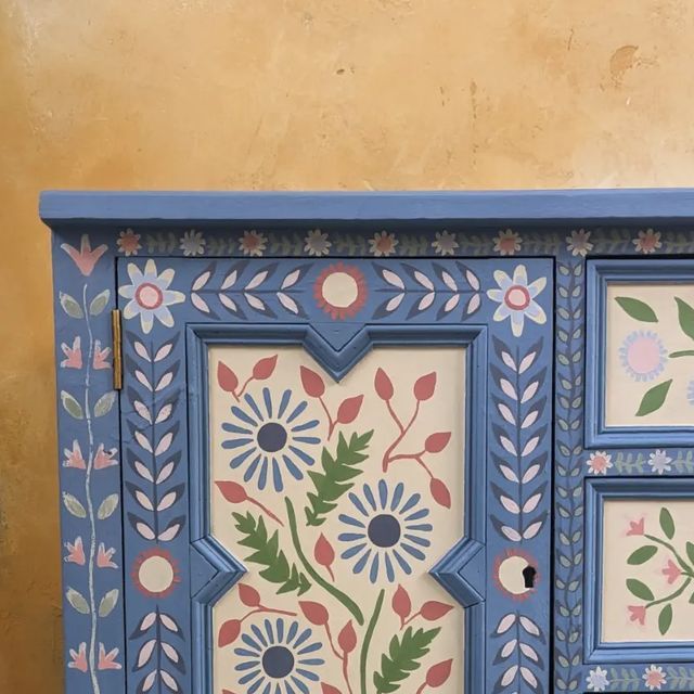 a painted cabinet with flowers and leaves on it