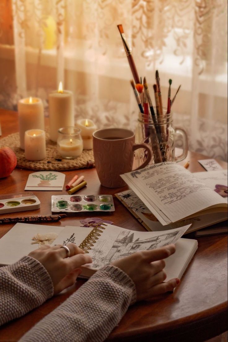 a person sitting at a table with some books and pencils on top of it