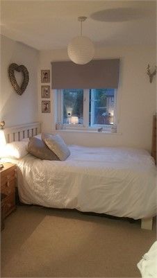 a bedroom with a bed, dresser and two lamps on either side of the window