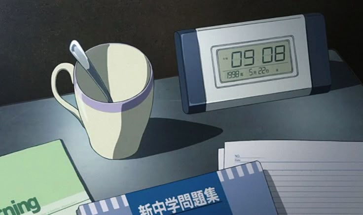 an alarm clock sitting on top of a desk next to a cup and notebooks