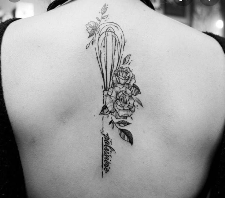 the back of a woman's shoulder with flowers and arrows on her left side