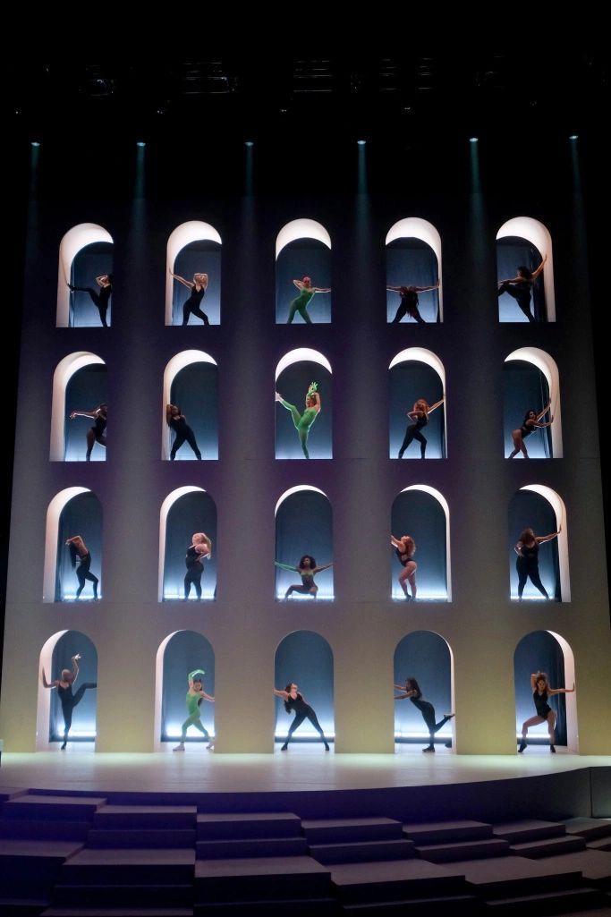 dancers on stage with spotlights in the middle and one person standing up behind them